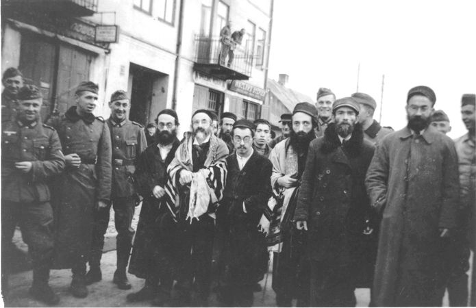 Smiling German soldiers surround a group of religious Jewish men on the street in Minsk